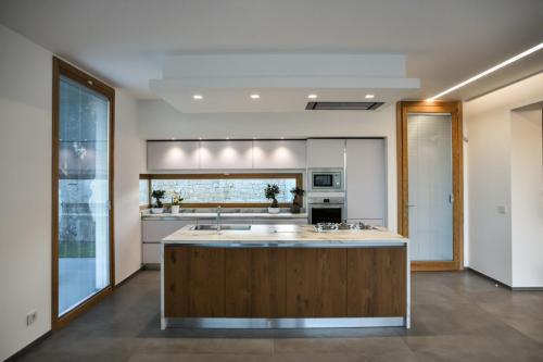 1. Cucina a parete laccata bianco opaco con top in gres, isola in rovere nodato con top e laterali in gres-min
