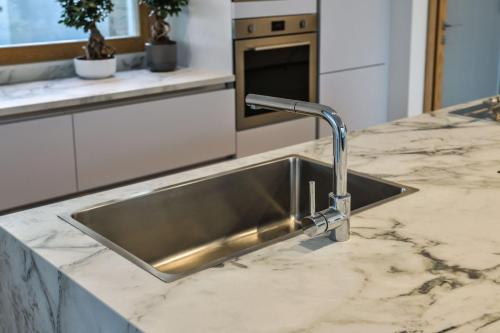 2. Cucina a parete laccata bianco opaco con top in gres, isola in rovere nodato con top e laterali in gres-min