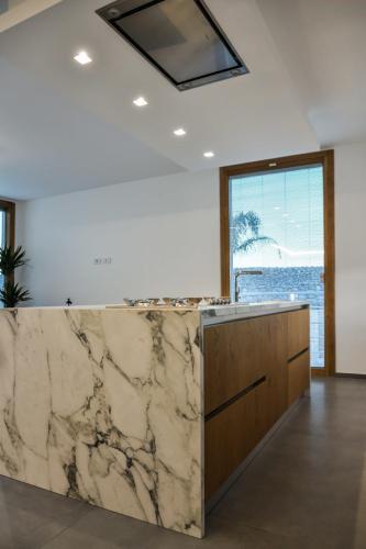 3. Cucina a parete laccata bianco opaco con top in gres, isola in rovere nodato con top e laterali in gres-min