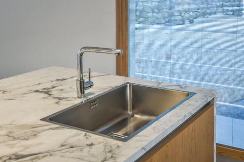 4. Cucina a parete laccata bianco opaco con top in gres, isola in rovere nodato con top e laterali in gres-min