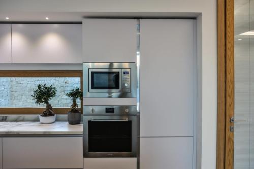 5. Cucina a parete laccata bianco opaco con top in gres, isola in rovere nodato con top e laterali in gres-min