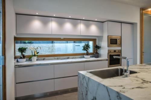 6. Cucina a parete laccata bianco opaco con top in gres, isola in rovere nodato con top e laterali in gres-min