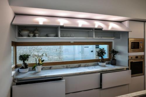 7. Cucina a parete laccata bianco opaco con top in gres, isola in rovere nodato con top e laterali in gres-min